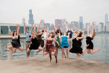 Groupe de danseurs sautant joyeusement en extérieur, bras levés