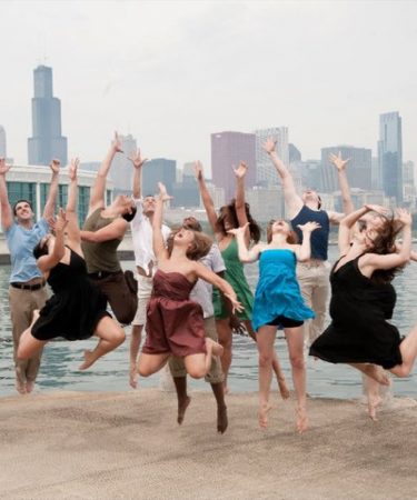 Groupe de danseurs sautant joyeusement en extérieur, bras levés