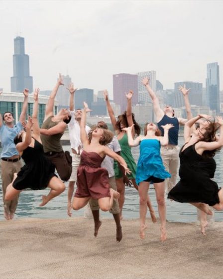 Groupe de danseurs sautant joyeusement en extérieur, bras levés