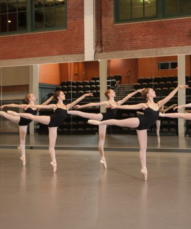 Jeunes danseuses en cours de danse, arabesque à la barre face au miroir