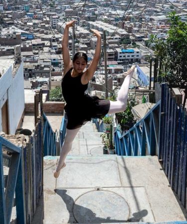Jeune danseuse en plein saut, extension de jambe, sur un escalier extérieur