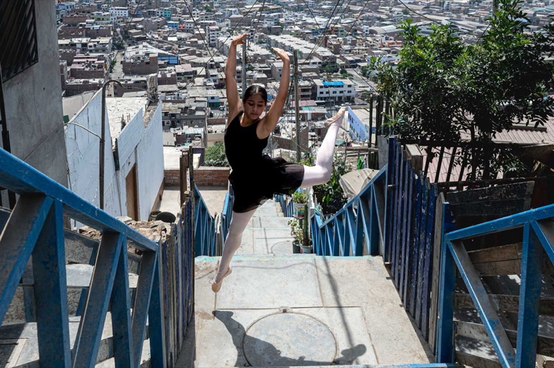 Jeune danseuse en plein saut, extension de jambe, sur un escalier extérieur